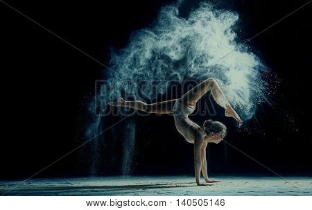 Graceful young woman dancing in cloud of dust