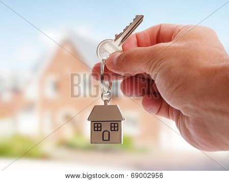 Holding house keys on house shaped keychain in front of a new home