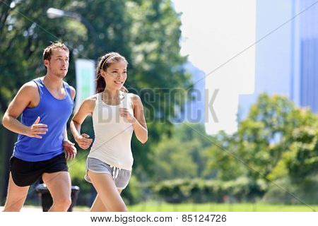 Runners jogging in New York City Central Park, USA. Healthy couple of new yorkers athletes running in summer sun working out a cardio exercise on Manhattan, United Sates of America.