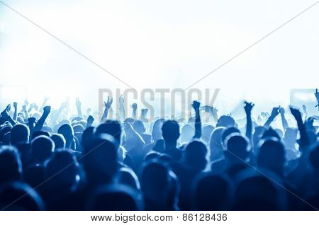 silhouettes of concert crowd in front of bright stage lights