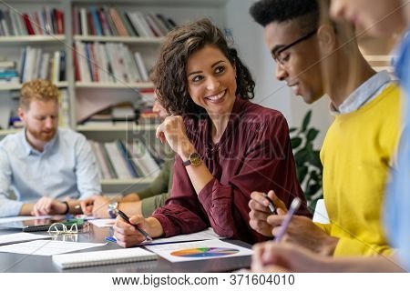 Multiethnic business people discussing together their strategy. Happy businesswoman showing marketing strategy african businessman. Creative business team talking and smiling during brainstorming.