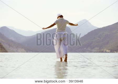 Woman Tiptoeing Through Water By Mountains