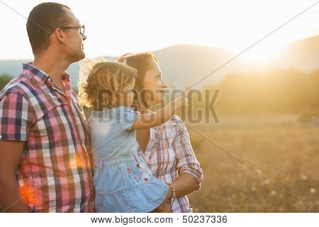 Glückliche Mutter, Vater und Tochter im Sonnenuntergang