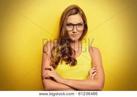 Beauty portrait of a happy young woman in spectacles and bright yellow dress over yellow background. Beauty, fashion. Optics.