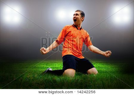 Happiness football player after goal on the field of stadium with light