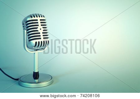 Old metal microphone on light blue background