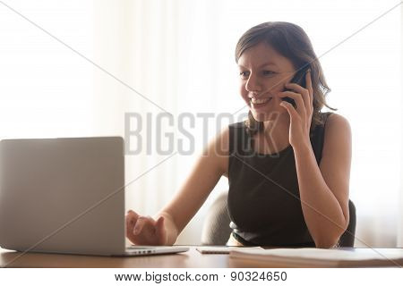 Young Girl Talking On Smartphone And Typing On Laptop