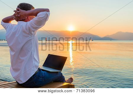 Recreational Entrepreneur. Man With Laptop In The Morning On The Beach Working