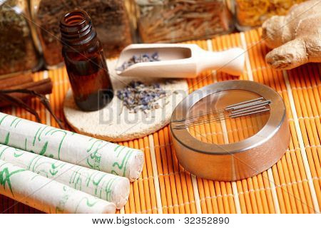 Acupuncture needles, moxa sticks, lavender petals with macerated oil, giner and herbs in jars. TCM Traditional Chinese Medicine concept photo