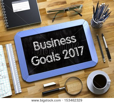 Business Goals 2017 on Small Chalkboard. Business Goals 2017 Handwritten on Blue Small Chalkboard. Top View of Wooden Office Desk with a Lot of Business and Office Supplies on It. 3d Rendering.