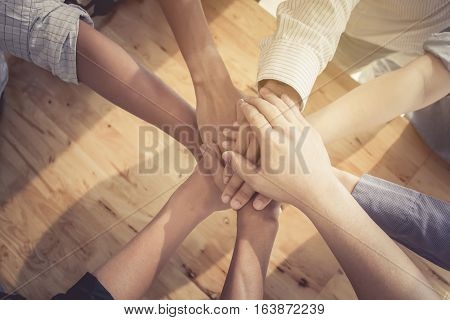 Group of people putting their hands working together on wooden background in office. group support teamwork cooperation concept.