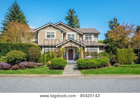 Luxury house with nicely trimmed front yard lawn in a residential neighborhood. Home exterior.