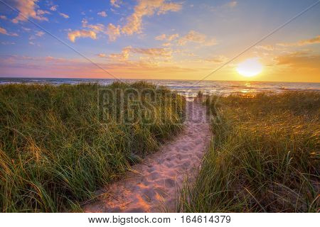 Path To A Sunset Beach. Winding trail through dune grass leads to a sunset beach on the coast of the inland sea of Lake Michigan. Hoffmaster State Park. Muskegon, Michigan.