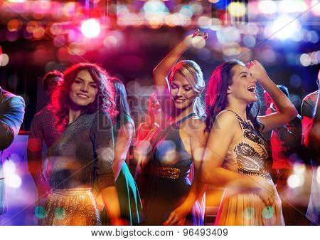 party, holidays, celebration, nightlife and people concept - happy friends dancing in club with holidays lights