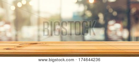 Wooden board empty table top blurred background. Perspective brown wood table over blur in coffee shop background. Panoramic banner - can be used mock up for montage products display or design.