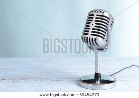 Vintage microphone on table on light blue background