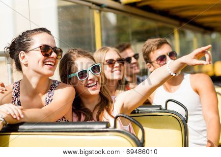 friendship, travel, vacation, summer and people concept - group of smiling friends traveling by tour bus