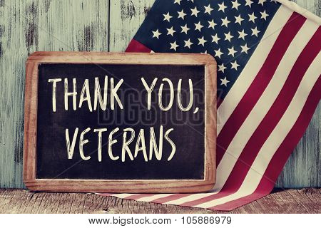 the text thank you veterans written in a chalkboard and a flag of the United States, on a rustic wooden background