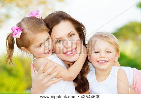 Bild der jungen Mutter umarmt von zwei kleinen Kindern, Closeup Portrait of happy Family, süße Brünette