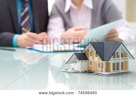 Businessman signs contract behind home architectural model