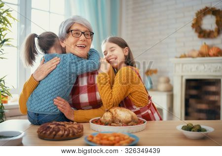 Happy Thanksgiving Day! Autumn feast. Family sitting at the table and celebrating holiday. Traditional dinner. Grandmother and granddaughters.                               