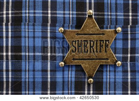 Sheriff star badge attached on blue plaid cowboy shirt