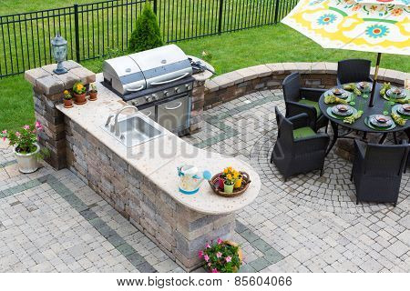 Outdoor Kitchen And Dining Table On A Paved Patio