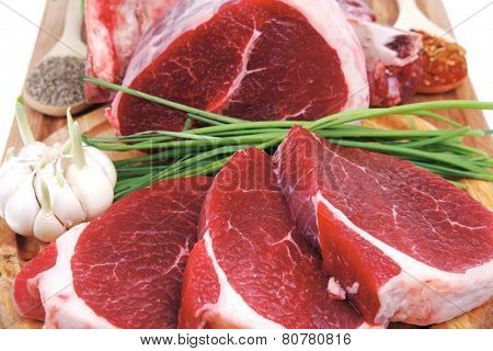 fresh meat : raw uncooked fat lamb pork rib and fillet with green stuff and red chili pepper on wooden plate isolated over white background