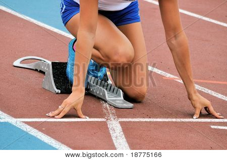 Female athlete in starting position on an athletic track