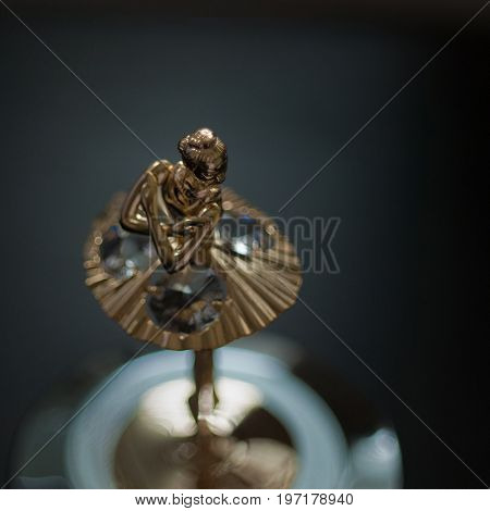 Top view of ballerina statuette on music box. Dark photo grain aded.