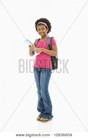 African American girl holding books and wearing backpack smiling at viewer.