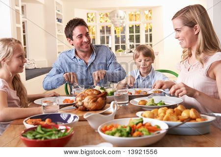 Glückliche Familie mit gebratenem Huhn Abendessen am Tisch