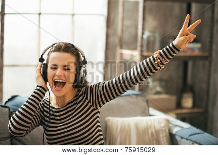 Cheerful Young Woman Listening Music In Headphones In Loft Apart