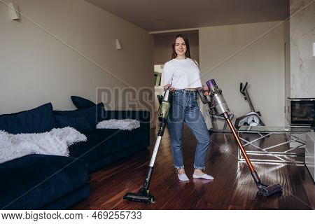 Young Maid Cleaning Carpet With Vacuum Cleaner At Home