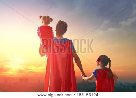 Happy loving family. Dad and his daughters are playing outdoors. Daddy and his children girls in an Superhero's costumes. Concept of Father's day.