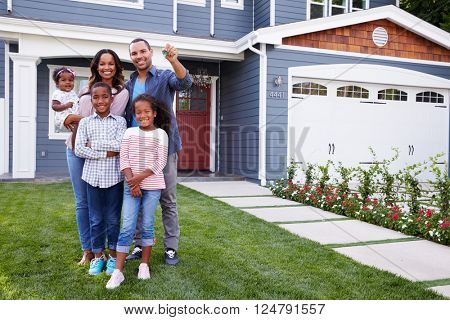 Happy black family standing outside their house, dad holding the key