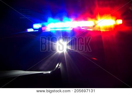 Red and Blue Emergency Lights Flashing on Police Car at Night