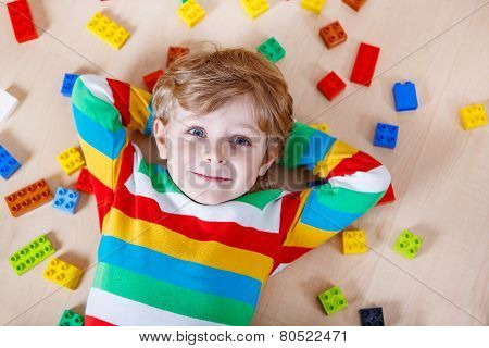 Little Blond Child Playing With Lots Of Colorful Plastic Blocks Indoor