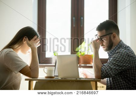 Stress at work: millennial businessman and businesswoman feeling confused and frustrated in office. Coworkers having headache, worrying about problems and failure in job