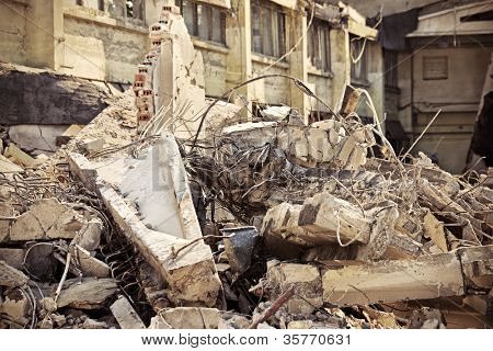 A picture of o heap of rubble and a demolished building in the background