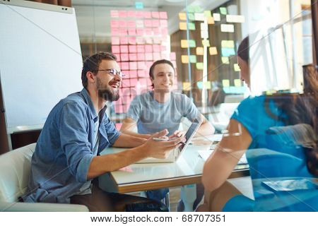 Young business partners sharing and discussing ideas at meeting in office