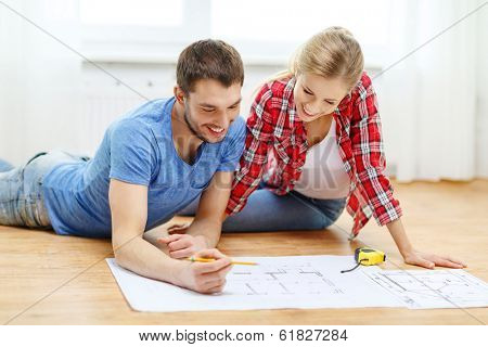 repair, building, renovation and home concept - smiling couple looking at blueprint at home