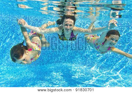 Happy smiling family underwater in swimming pool. Mother and children swim and having fun