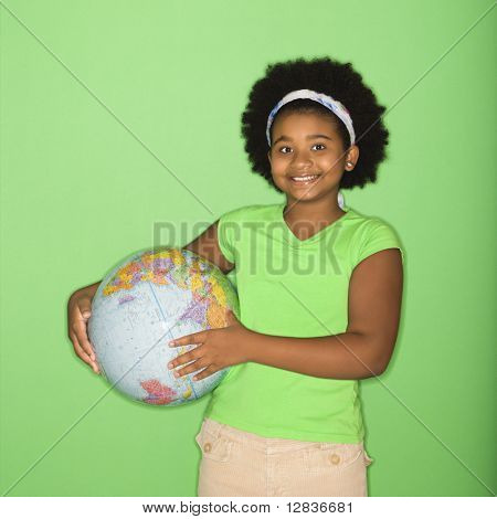 African American girl holding globe at hip and smiling at viewer.