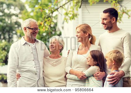 family, happiness, generation, home and people concept - happy family standing in front of house outdoors