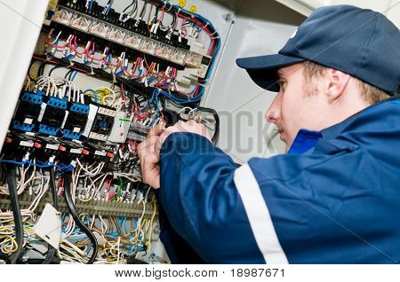 One electrician working on a industrial panel mounting, assembling, adjusting new voltage wiring