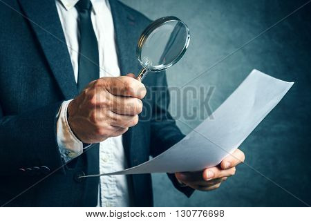 Tax inspector investigating financial documents through magnifying glass forensic accounting or financial forensics inspecting offshore company financial papers documents and reports.