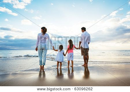 Happy young family watching the sunset at the beach.  Happy Family Lifestyle 