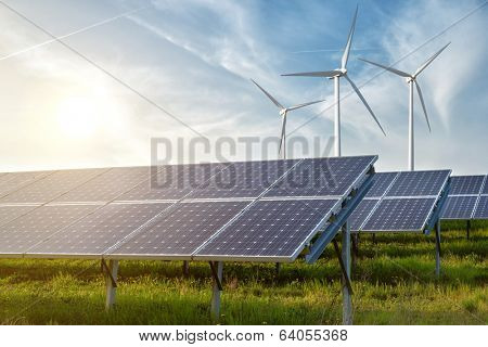 solar panels and wind generators under blue sky on sunset