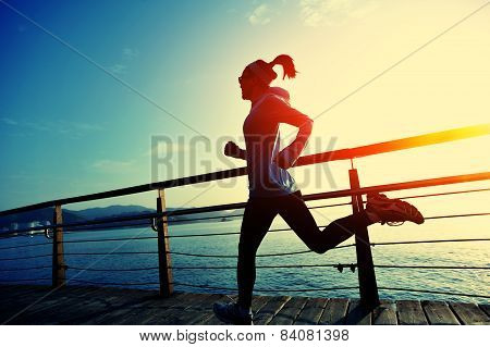 healthy lifestyle sports woman running on wooden boardwalk sunrise seaside